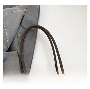 Detail of brown faux leather tote handle showing fine stitching and craftsmanship