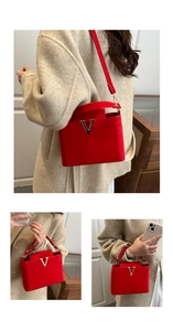 Detail of red leather handbag with gold V-buckle and adjustable shoulder strap