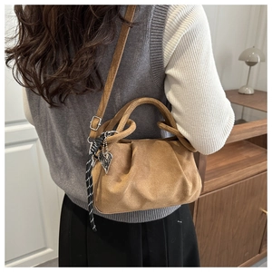 Sac à main plissé en daim marron avec pendentif cœur argenté dans un décor de maison