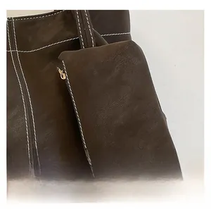 Close-up of deep brown leather tote bag with white stitching and small side pouch