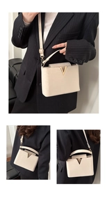 Detail of cream rectangular flap bag with gold V-buckle and adjustable leather strap