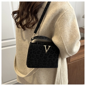 Detail of leopard print handbag featuring a gold V-shaped buckle on textured fabric