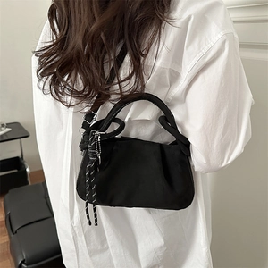 Détail du sac bandoulière noir plissé avec breloque en corde tissée et fini mat
