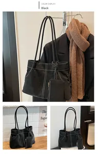 Detail of minimalist black leather tote bag with contrast white stitching and small pouch