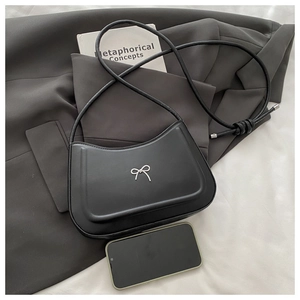 Detail of black matte leather shoulder bag with silver bow accent and metallic knot