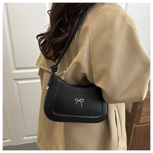 Close-up of black PU leather shoulder bag featuring a silver metal bow detail and knot strap