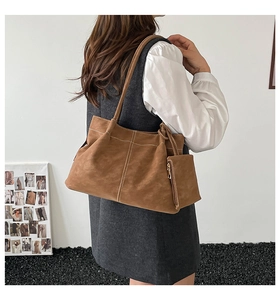 Close-up of brown suede tote bag featuring white contrast stitching and a side coin pouch