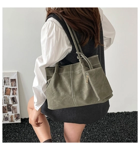 Macro detail of large olive green suede tote bag with contrast white stitching accent