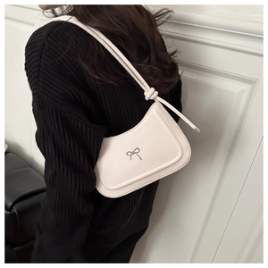 Detail view of cream white hobo bag with silver bow ornament and leather texture