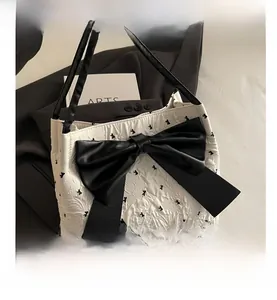 Close-up of white tote bag with large black 3D bow and textured polka dot fabric