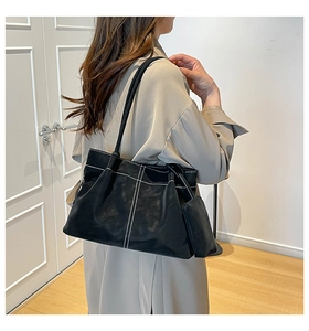 Detail of black suede tote bag featuring white contrast stitching and mini pouch
