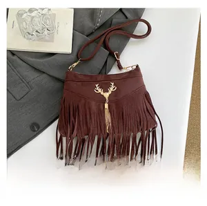 Gros plan sur le sac à franges en daim marron avec tête de cerf dorée et chaîne