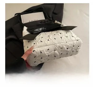 Detail of white pleated tote bag with black bows and long shoulder strap in urban style