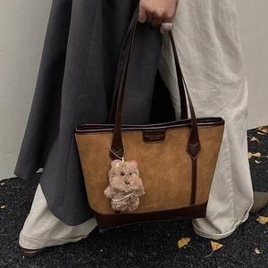 Brown textured tote bag with embossed pattern and cute bear charm shown in street style