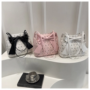 Detailed view of textured tote bags with large bows in white and pink color options