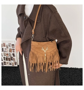 Detail of bohemian brown suede crossbody bag with fringe and golden antler metal ornament