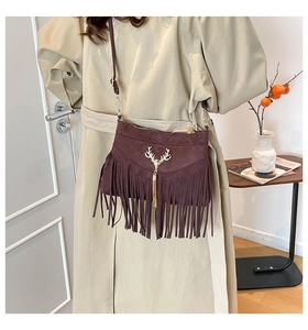 Détail du sac bandoulière en daim marron avec de longues franges et un pompon tête de cerf
