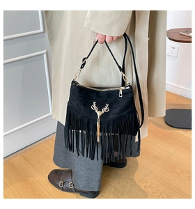 Detail of black suede shoulder bag with long fringes and golden deer head pendant