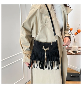 Détail du sac bandoulière en daim noir avec longues franges et emblème de cerf doré