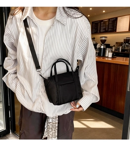 Minimalist black nylon tote bag shown in a cozy cafe setting for daily commuting