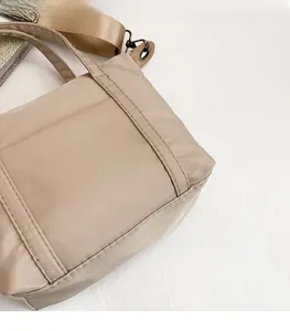 Close-up of beige nylon crossbody bag showing water-resistant fabric and fine stitching