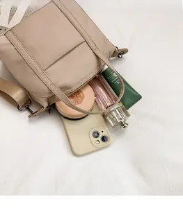 Internal view of the beige nylon crossbody bag showing its large storage capacity for items