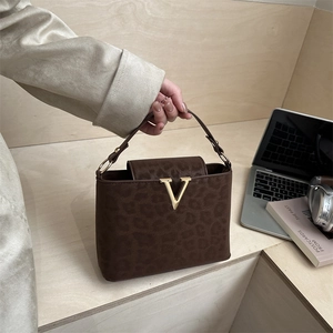 Deep brown leopard print handbag with golden V buckle and top handle in a lifestyle setting