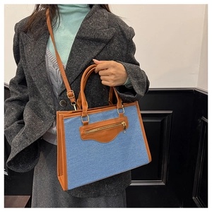 Detalle de bolso tote de denim y cuero con cremallera dorada mostrado en modelo mujer