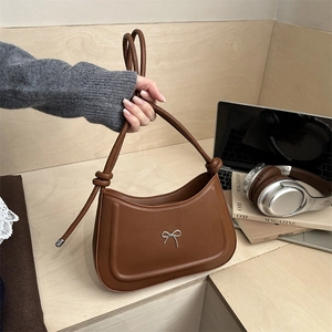 Minimalist dark brown crescent underarm bag with silver bow accent and knotted strap