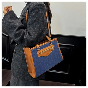 Vista lateral de bolso tote de mezclilla en modelo con abrigo gris de textura suave