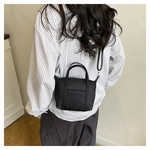 Detailed back view of model wearing a black nylon crossbody bag with adjustable strap