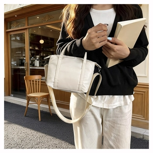 Close-up of beige nylon tote bag with adjustable strap in outdoor cafe setting
