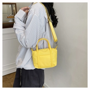 Detail of bright yellow nylon crossbody bag with reinforced handles and metal buckles