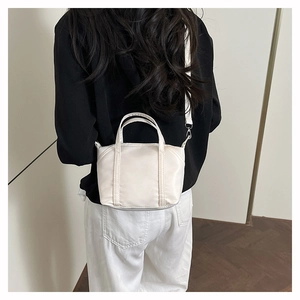 Rear view of a model wearing a compact white nylon crossbody bag with adjustable strap
