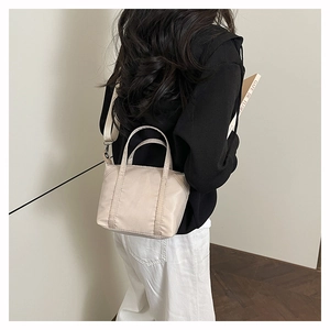 Close-up of beige nylon crossbody bag with adjustable strap on a female model