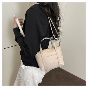 Side view of beige nylon crossbody bag on model showing adjustable strap and large capacity