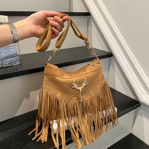 Brown suede shoulder bag with metal deer pendant and tassels in a stylish scenery