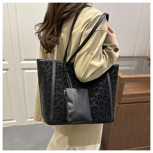 Detail of black leopard print tote bag with sub-bag on model in modern home setting