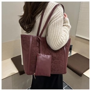 Dettaglio della borsa tote bordeaux maculata con pochette indossata su maglione