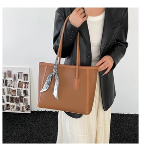Dettaglio della borsa tote in pelle marrone scuro con foulard in seta sulla maniglia