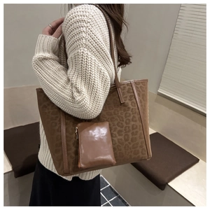 Detail of leopard print tote bag with brown leather trim and matching small pouch