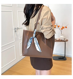 Dettaglio della borsa tote marrone scuro con motivo litchi e foulard sul manico