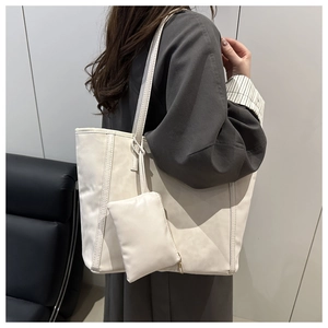 Detailed view of white faux leather tote bag with small coin purse shown on a model