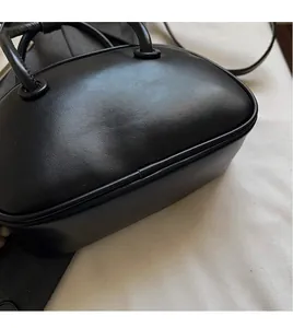 Gros plan d'un sac bowling en cuir noir montrant des coutures fines et deux poignées