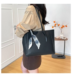 Detailed view of black pebbled leather tote bag with a decorative blue printed silk scarf