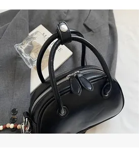 Vue de dessus d'un sac bowling en cuir noir brillant avec perles sur un blazer gris