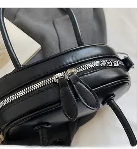 Détail de la fermeture éclair en métal argenté sur un sac à main en cuir noir lisse