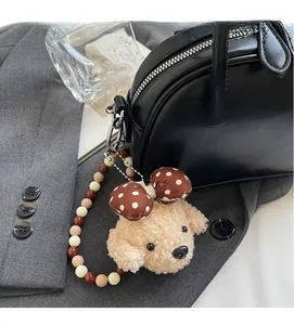 Détail d'un charm de sac chien en peluche avec nœud et perles sur sac en cuir noir