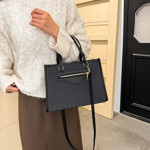 Bolso tote de mezclilla negra minimalista con correas de cuero y cremallera metálica