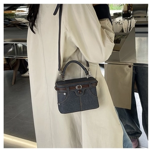 Detail of creative dark grey denim box bag with vintage pocket and brown leather trim